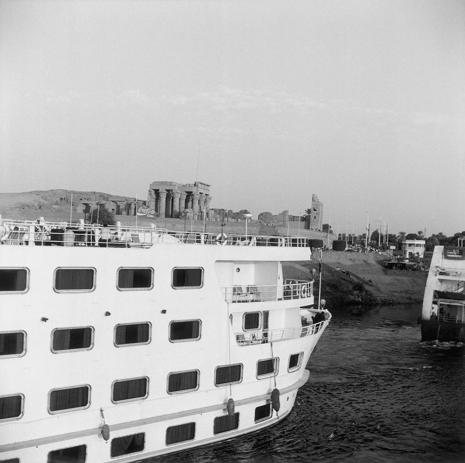 Ein großer Dampfer auf dem Suezkanal, im Hintergrund sieht man Antike ägyptische Bauten.