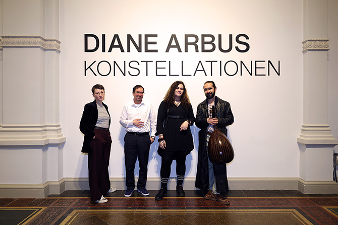 Die Autor*innen des Abends stehen gemeinsam unter dem Schriftzug der Ausstellung ‚Diane Arbus – Konstellationen‘.